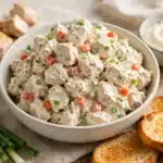 Ensalada de Pollo cremosa en un bol con tostadas, pollo en trozos y cebollino fresco