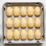 Esponjosidad y Frescura: bandeja de horno con papel vegetal llena de galletas rectangulares doradas de mantequilla espolvoreadas con azúcar