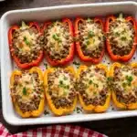 Pimientos Rojos Rellenos de Carne: mitades de pimientos rojos y amarillos rellenos de carne y verduras con queso gratinado en bandeja de horno